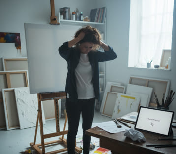 Job or Business — woman stressed at an easel with a blank canvas; tablet shows Project Proposal